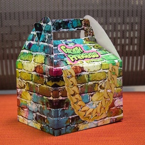 Puede incluir: Una caja de cart&oacute;n colorida con un patr&oacute;n de ladrillo y un dise&ntilde;o de cadena dorada. La caja tiene un asa y dice "Fresh Princess" en la parte delantera.