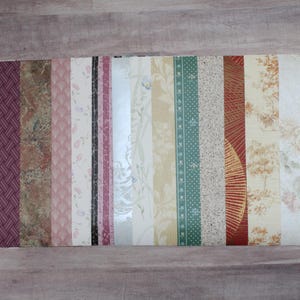 May include: A collection of 16 different wallpaper samples, featuring a variety of patterns and colors, including floral, geometric, and abstract designs. The samples are arranged in a row, with the colors ranging from white to dark red.