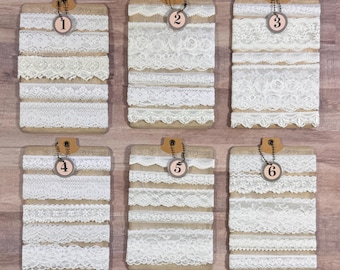 May include: Six wooden clipboards displaying various white lace trims. Each clipboard has a different assortment of lace, numbered 1 through 6. The lace designs include floral, scalloped, and geometric patterns, perfect for crafting and sewing projects.