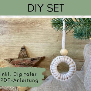 Könnte beinhalten: Ein DIY-Set mit einem Makramee-Kranz-Ornament und einem Holzstern. Der weiße Kranz ist kreisförmig, mit einer Holzkugel. Der Stern ist aus Rinde gefertigt. Der Text "DIY SET" steht oben und "Incl. Digitaler PDF-Anleitung" unten.