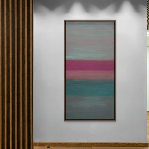 May include: Abstract art piece in a wooden frame. The artwork features horizontal bands of color: gray, pink, teal, and gray. The painting is displayed on a white wall in a room with wooden accents.