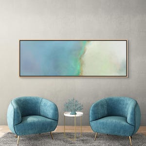 May include: A panoramic rectangular wall art piece featuring an abstract blend of soft blue, teal, and cream tones. The painting is enclosed in a thin, light-colored wooden frame, showcasing smooth color transitions and a serene, ethereal aesthetic.