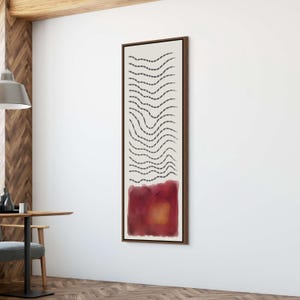 May include: Abstract art print in a dark wood frame. The artwork features a cream-colored background with black dashed lines and a red and orange watercolor block at the bottom. The artwork is rectangular and vertically oriented.