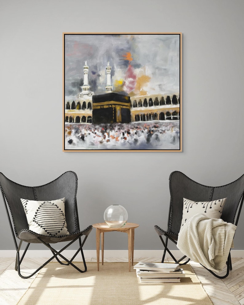 Holy Kaaba Wall Art Canvas Print hanging on a white wall, two black chairs, and a small table in front of it, creating a cozy and inviting atmosphere.