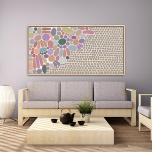 May include: A rectangular framed wall art piece featuring an abstract pattern of various sized circles and oval shapes in muted tones of pink, purple, blue, green, and beige, transitioning into a dense field of small grey dots on the right side.