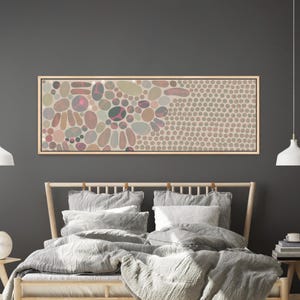 May include: A rectangular wall art piece in a light wood frame featuring an abstract pattern of rounded shapes in shades of beige, pink, and dark gray on the left, transitioning into a dense grid of small, uniform beige dots on the right side.