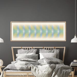 May include: A long, rectangular framed wall art piece featuring a repeating geometric pattern of vertical bars in soft gradients of pale yellow, light blue, and cream. The artwork is enclosed in a thin, light-toned wooden frame with a clean edge.