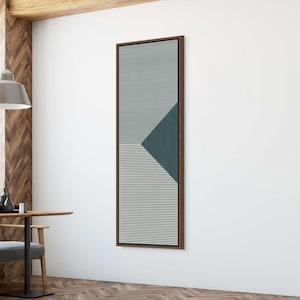 May include: Vertical framed abstract art piece. The artwork features a geometric design with vertical and horizontal lines in shades of teal and gray, with a dark brown frame. The art is mounted on a white wall.