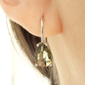 May include: A pair of silver earrings with a pear-shaped green gemstone.