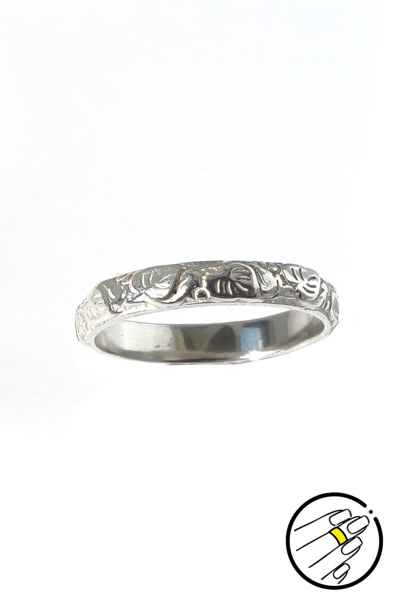 May include: A silver band ring with an intricate floral design.