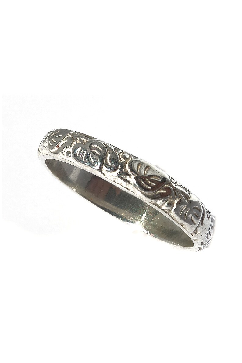 May include: A silver band ring with an intricate floral design.