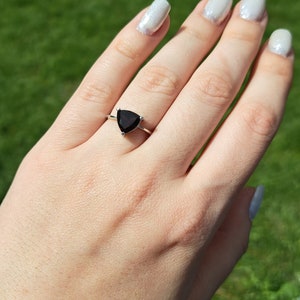 Puede incluir: Un anillo de plata con una piedra preciosa triangular de color rojo oscuro.