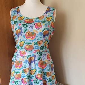 May include: A light blue sleeveless dress with a pattern of sloths on donuts, watermelons, and pineapples. The dress has a white tulle underskirt.