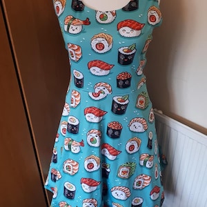 May include: A sleeveless blue dress with a pattern of various sushi rolls with cute faces. The dress has a fitted bodice and a flared skirt.