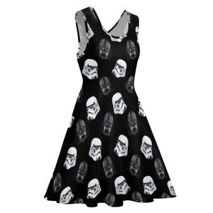 May include: Black sleeveless dress featuring a repeating pattern of white Stormtrooper helmets and black Darth Vader helmets. The dress has a V-neck and a flared skirt, perfect for fans of the Star Wars franchise.