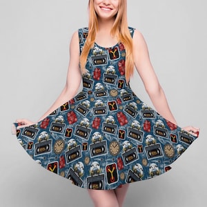 Puede incluir: Vestido azul sin mangas con un patrón repetido de cintas VHS retro, guantes de boxeo rojos, relojes y la letra "Y". El vestido tiene un escote redondo y una falda acampanada, perfecto para un evento casual o temático.