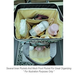 May include: A black and gray diaper bag with a floral pattern. The bag has several inner pockets and a mesh front pocket. The bag is open and filled with baby supplies, including diapers, bottles, and a sippy cup.