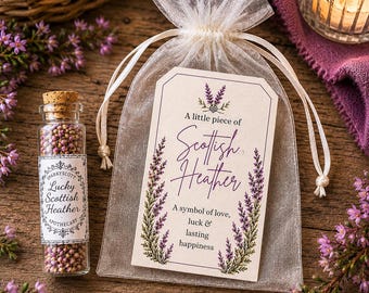 May include: A clear glass vial filled with small purple heather flowers, topped with a cork stopper and a label reading Lucky Scottish Heather. Beside it, a sheer white organza drawstring bag features a tag with purple heather illustrations.