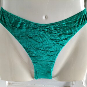 May include: Teal green satin underwear with a ruffled texture.