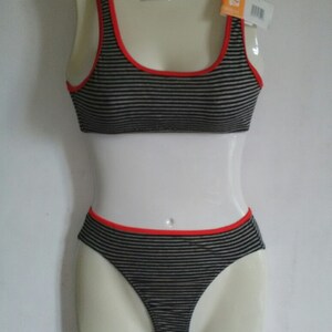 May include: Black and white striped underwear set with red trim. The top is a sports bra style with thin straps. The bottom is a bikini style with a low rise.