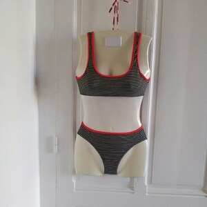 May include: Black and white striped bikini top and bottom with red trim. The bikini is displayed on a white mannequin.