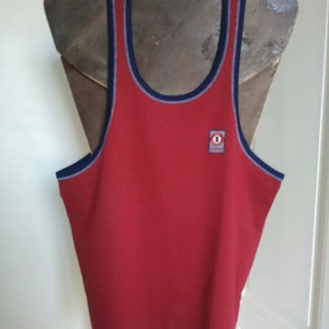 May include: Red sleeveless tank top with a blue and white trim around the neck and armholes. A small red and white logo with the number "1" is on the front of the shirt.