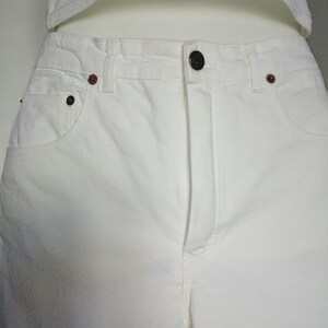 May include: White denim pants with a button fly and two front pockets.