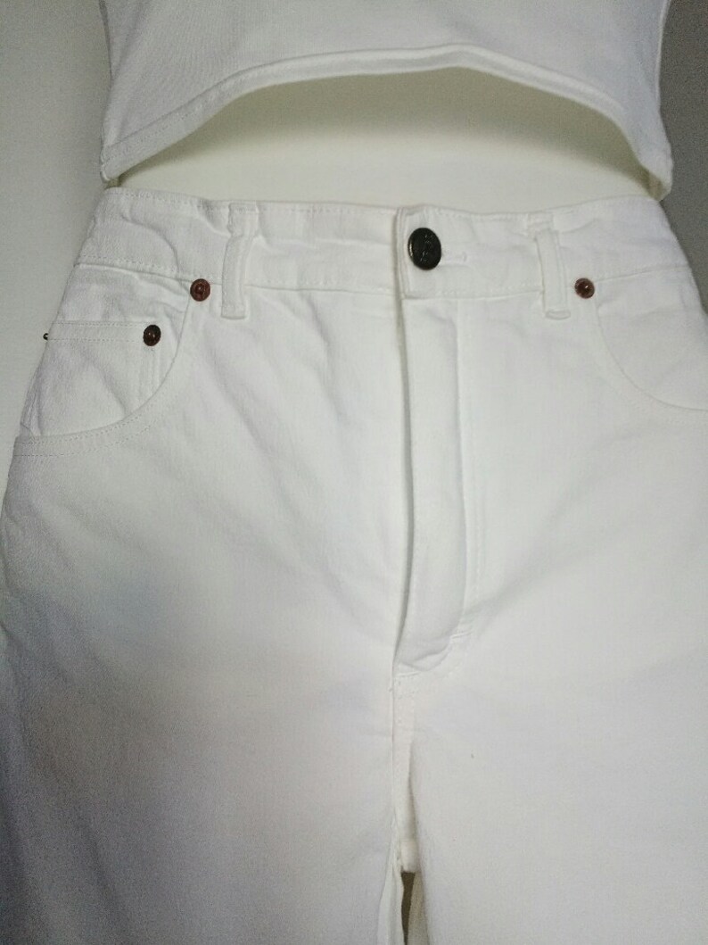May include: White denim pants with a button fly and two front pockets.