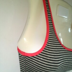 May include: A black and white striped sports bra with a red trim. The bra is on a white mannequin.