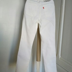 May include: White high-waisted jeans with a small "gallice" label on the back pocket.
