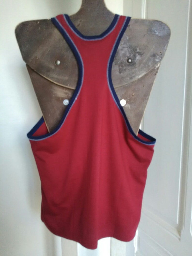 May include: Red sleeveless tank top with a navy blue trim around the neck and armholes.