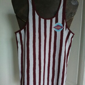 May include: White and burgundy striped tank top with a small blue and white logo that says "Authentic Fashion".