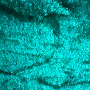 May include: Close-up of a teal blue fabric with a soft, fuzzy texture. The fabric has a subtle, swirling pattern.