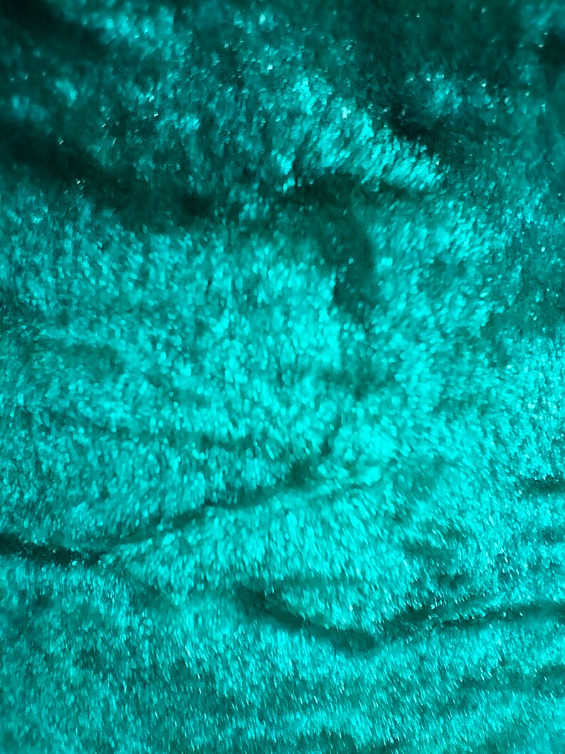 May include: Close-up of a teal blue fabric with a soft, fuzzy texture. The fabric has a subtle, swirling pattern.