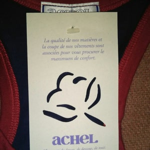 May include: A white tag with black text and a black graphic. The tag reads "La qualit&eacute; de nos mati&egrave;res et la coupe de nos v&ecirc;tements sont associ&eacute;es pour vous procurer le maximum de confort. achel V&ecirc;tements de dessus, de dessous, de nuit."