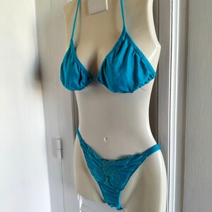 May include: A turquoise bikini with a butterfly design on the bottom. The bikini is displayed on a white mannequin.