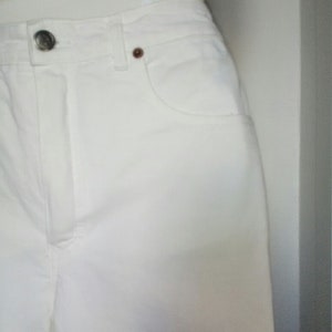 May include: White denim pants with a button fly and a front pocket.