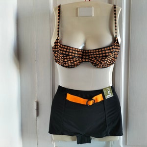 May include: Black and orange checkered bikini top with a black high-waisted bottom with an orange belt. The size tag reads "42".