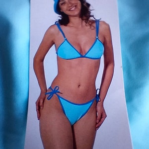 May include: A blue bikini with a triangle top and a tie-side bottom. The bikini is on a white background with the number 7608 printed on the bottom.