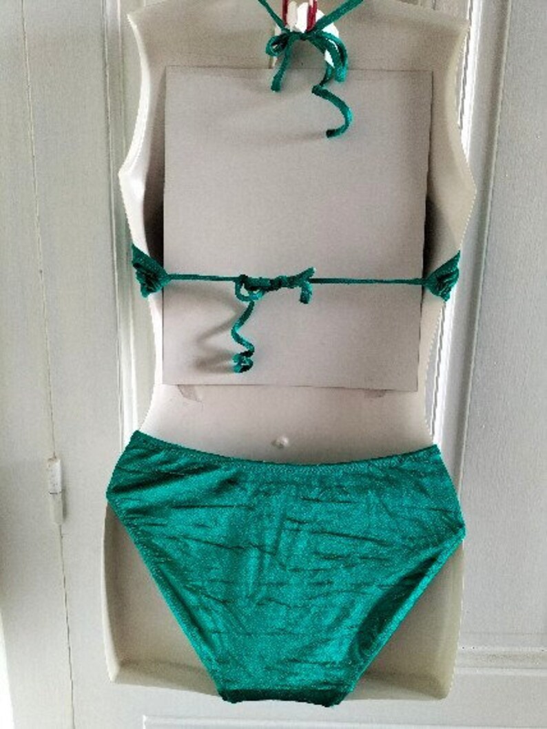 May include: A teal green bikini bottom with a high-cut leg and a smooth, silky texture.