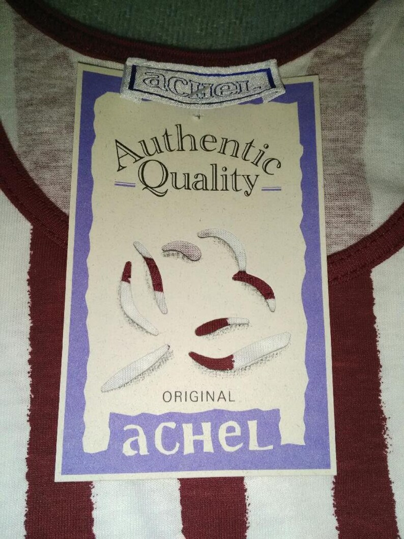 May include: A white and burgundy striped shirt with a tag that reads "Authentic Quality - Original aCHEL" and features a purple border and a graphic of five white and burgundy worms.