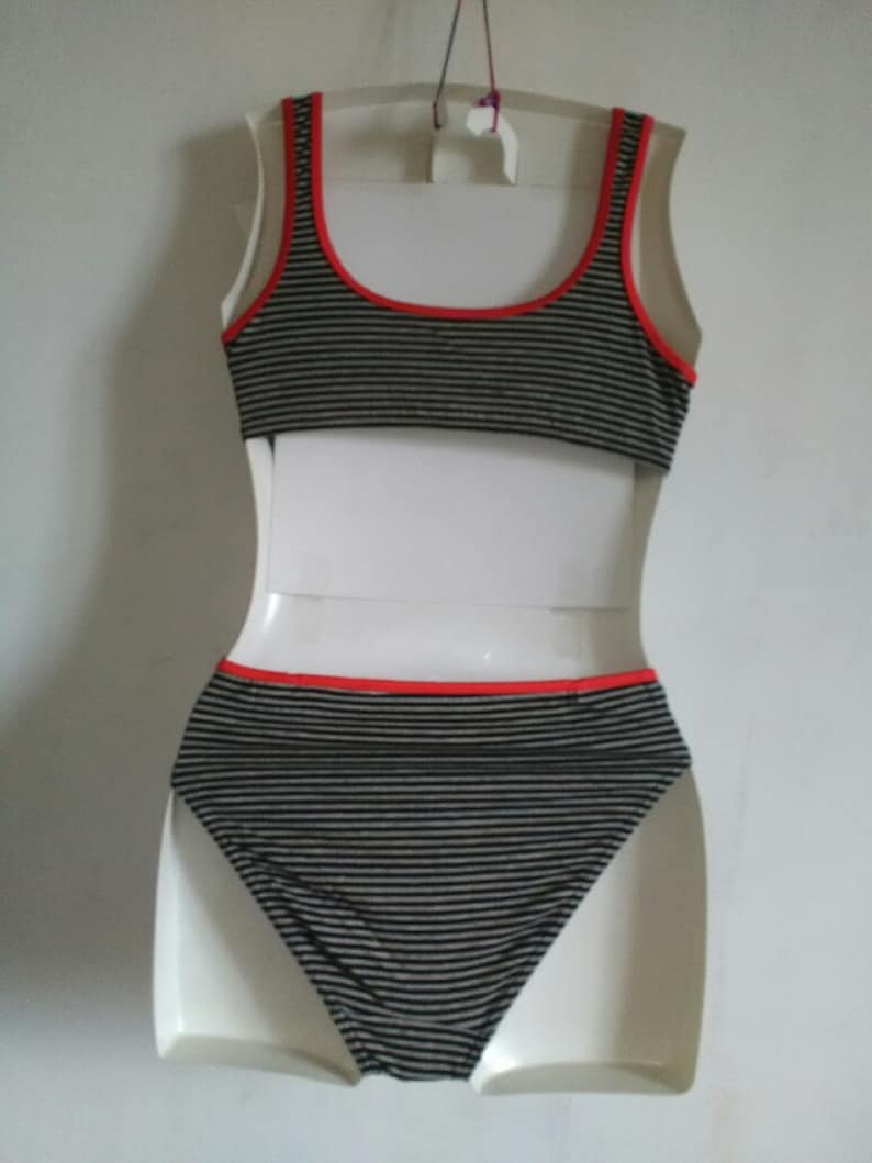 May include: Black and white striped bikini top and bottom with red trim. The bikini is on a white mannequin.