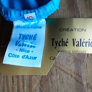 May include: A white tag with blue text that reads "Made in France" and "Tyche Valerio - Nice - C&ocirc;te d'Azur". A gold tag with black text reads "Creation Tyche Val&eacute;rie Marque D&eacute;pos&eacute;e".