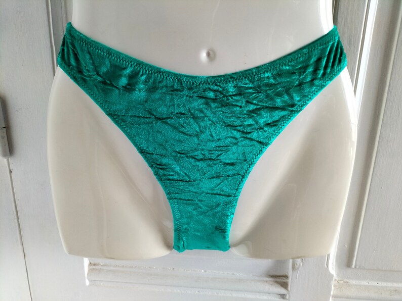 May include: Teal green satin underwear with a ruffled texture.