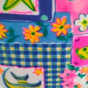 Puede incluir: Primer plano de una tela colorida con un dise&ntilde;o de patchwork. El patr&oacute;n incluye cuadrados azules, rosas y blancos con estrellas amarillas, flores y una luna creciente. La tela tiene un patr&oacute;n de cuadros y bordes florales.