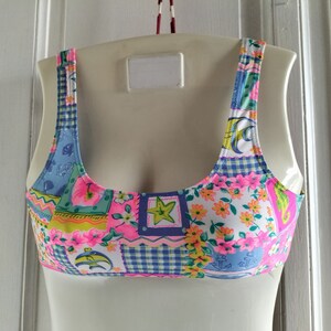 Puede incluir: Top de bikini patchwork colorido con una variedad de patrones, incluyendo motivos florales, cuadros y n&aacute;uticos. El top presenta una mezcla de colores rosa, azul, amarillo y blanco. Las correas y los bordes son rosas.