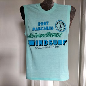 May include: A light blue sleeveless shirt with the text "Port Barcares Internationale Windsurf Mediterranee" and a logo for "Le Barcares Beach Club".