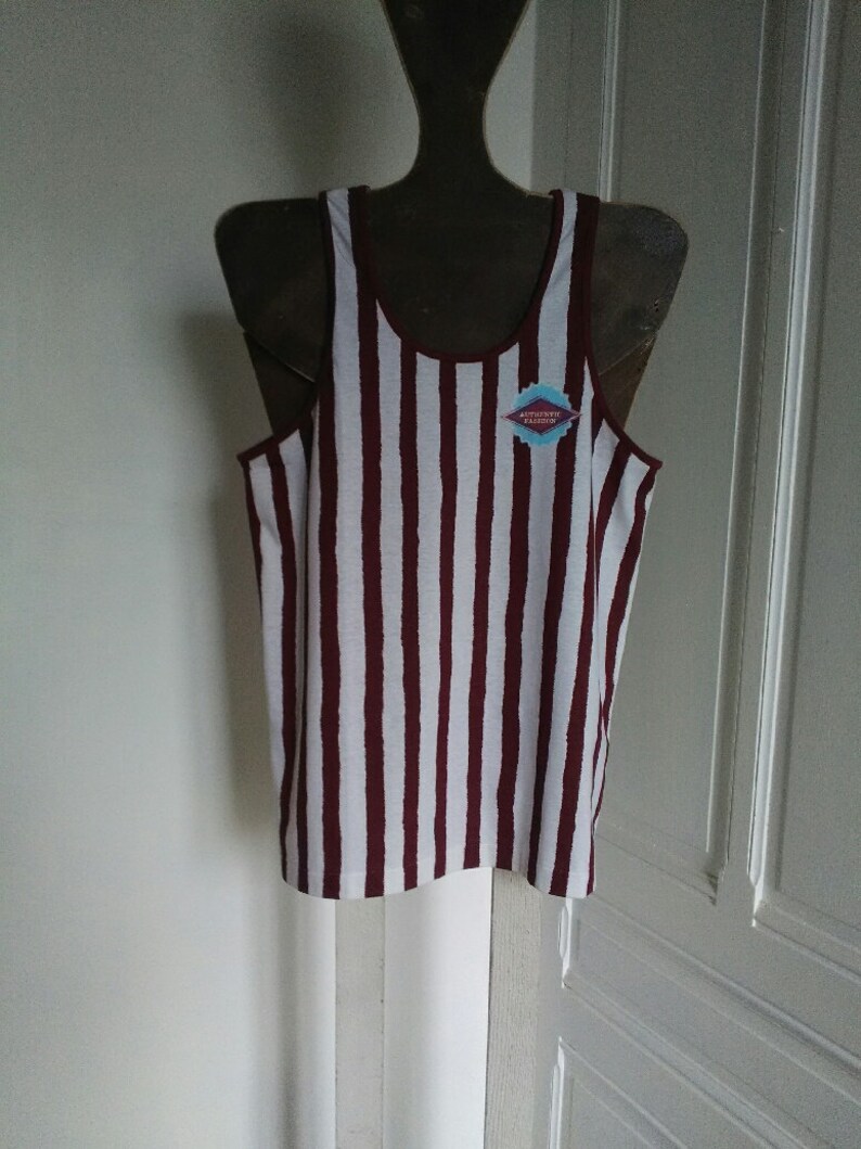 May include: White and burgundy striped tank top with a small blue and white patch that says "Authentic Vintage" on it.