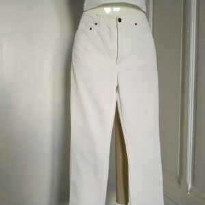 May include: White denim jeans with a straight leg fit.