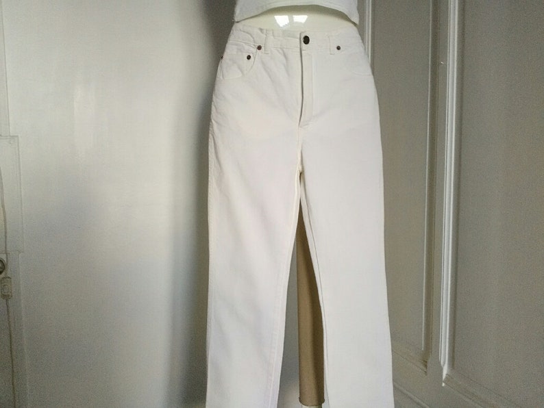 May include: White denim jeans with a straight leg fit.